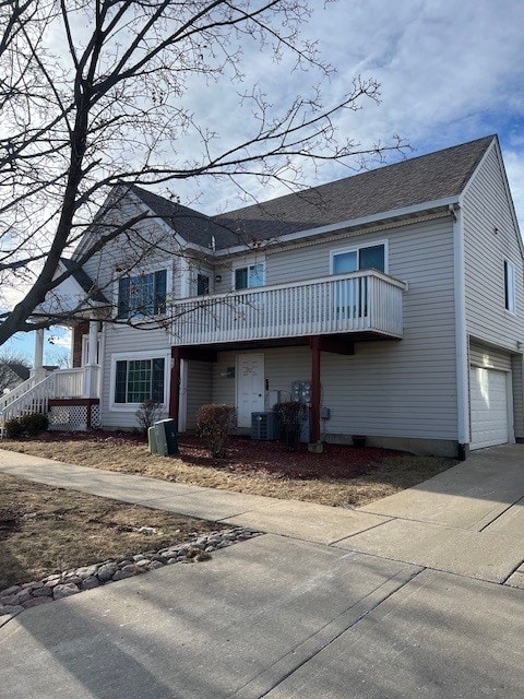 view of property featuring central AC unit, a garage, and a balcony