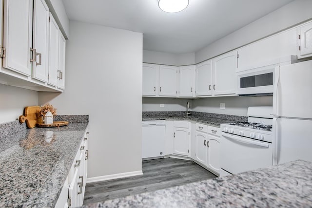 kitchen featuring sink, white cabinetry, dark hardwood / wood-style flooring, stone counters, and white appliances