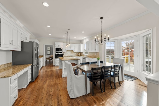 dining room with a chandelier, recessed lighting, wood finished floors, visible vents, and ornamental molding