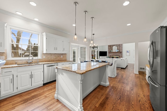 kitchen with stainless steel appliances, a kitchen island, a sink, and white cabinetry