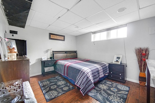 bedroom featuring baseboards, a paneled ceiling, and wood finished floors