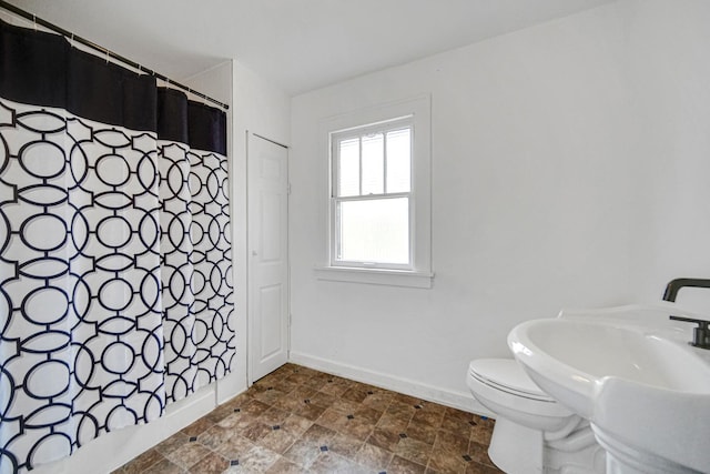 full bath with toilet, baseboards, stone finish flooring, and a shower with curtain