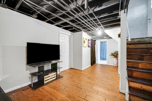unfurnished living room featuring stairs, baseboards, and wood finished floors