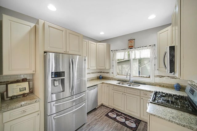 kitchen featuring a sink, appliances with stainless steel finishes, tasteful backsplash, and light wood-style flooring