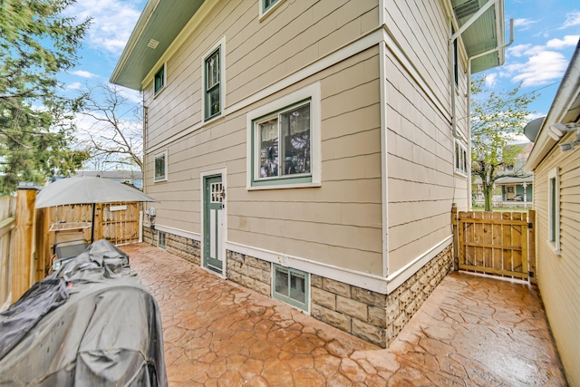 view of side of home featuring a patio, a gate, and fence