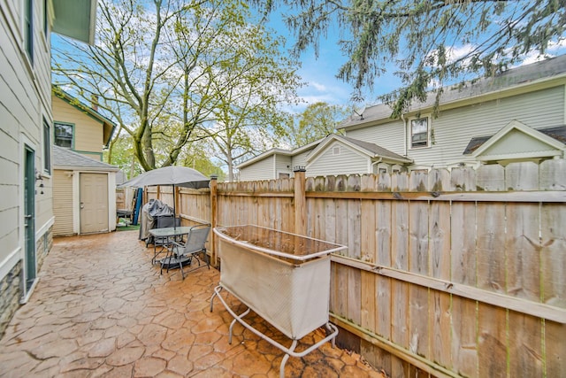 view of patio / terrace featuring fence, an outdoor structure, and a storage shed