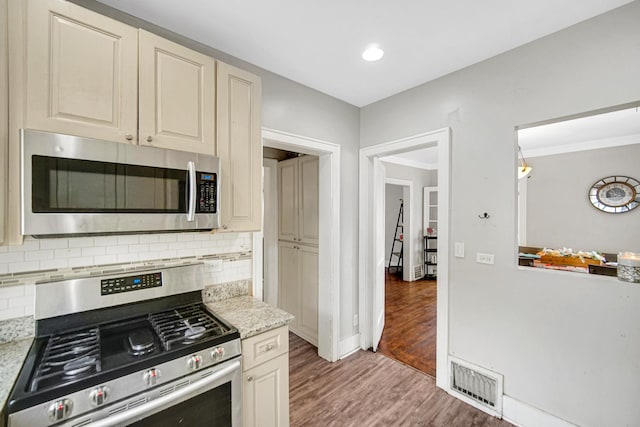 kitchen featuring visible vents, decorative backsplash, appliances with stainless steel finishes, and cream cabinetry