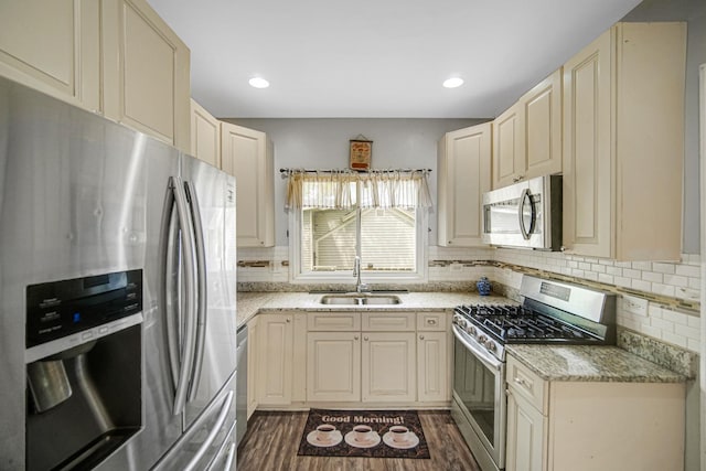 kitchen with a sink, appliances with stainless steel finishes, dark wood finished floors, and cream cabinetry