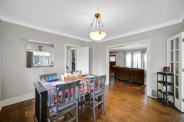 dining space with crown molding, baseboards, and wood finished floors