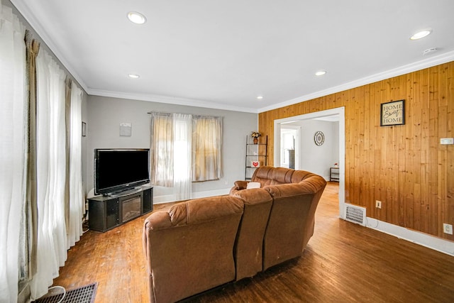 living room with crown molding, visible vents, and wood finished floors