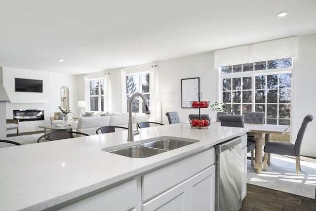 kitchen with sink, light stone counters, white cabinets, dark hardwood / wood-style flooring, and stainless steel dishwasher