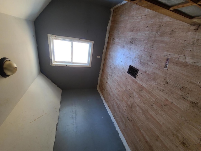 spare room featuring vaulted ceiling and concrete floors