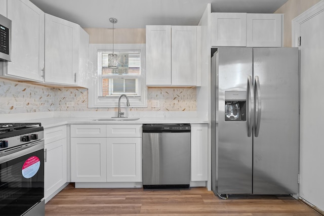 kitchen featuring stainless steel appliances, hanging light fixtures, sink, and white cabinets