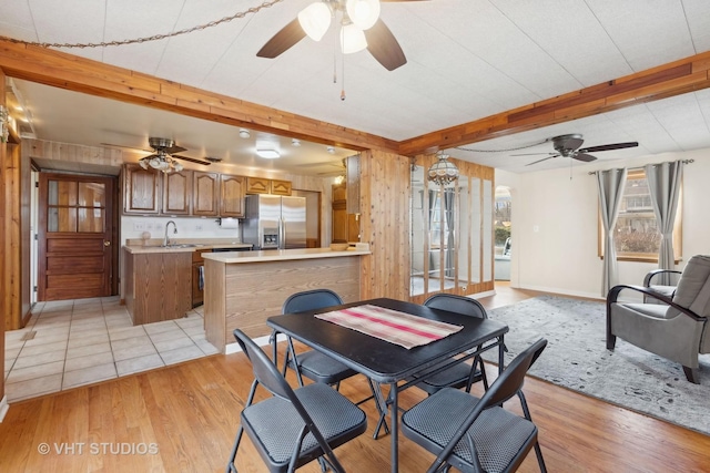 dining area with sink, light hardwood / wood-style floors, beamed ceiling, and ceiling fan