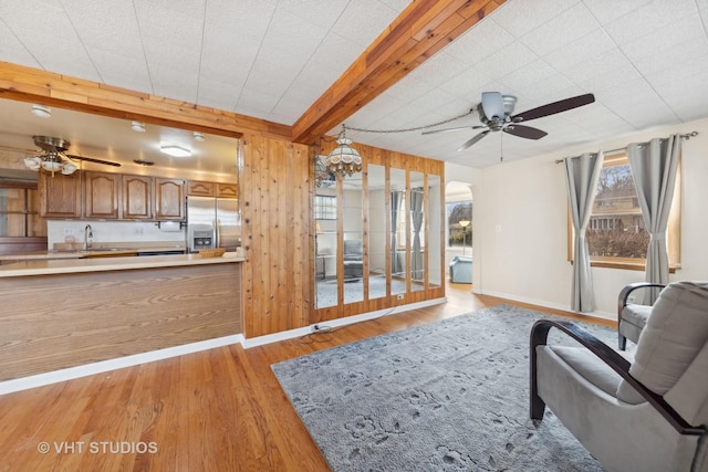 living room with beam ceiling, ceiling fan, and light wood-type flooring