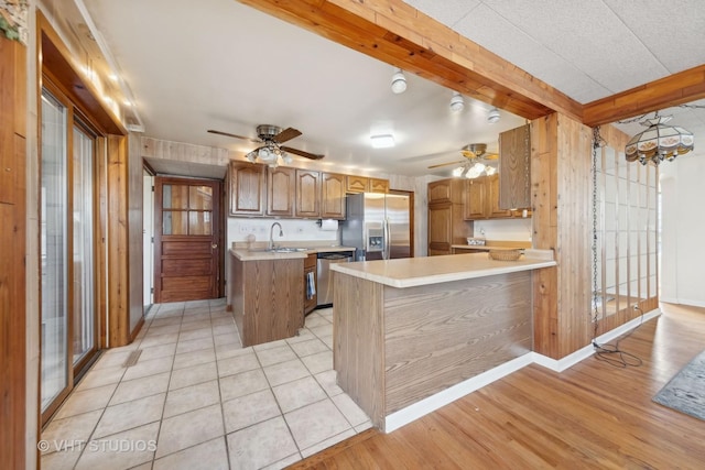 kitchen with beamed ceiling, sink, a center island, kitchen peninsula, and stainless steel appliances