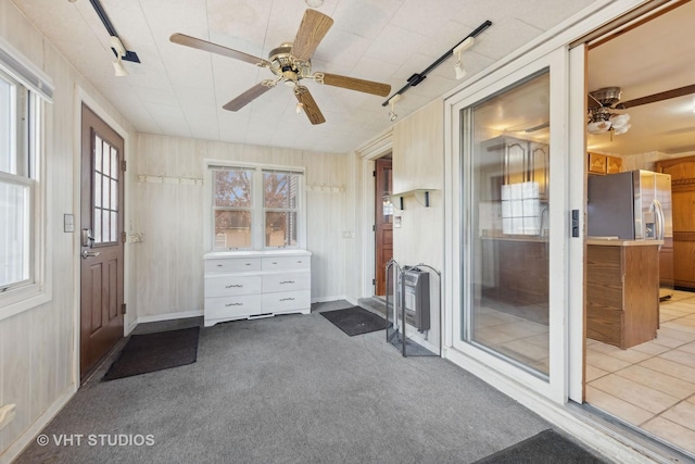 interior space featuring heating unit, track lighting, light colored carpet, and ceiling fan