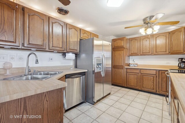 kitchen featuring stainless steel appliances, sink, light tile patterned floors, and ceiling fan