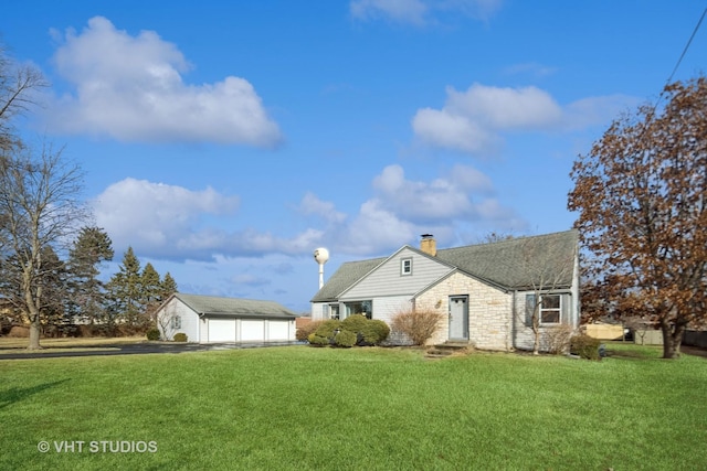 view of front of home with a garage, an outbuilding, and a front lawn