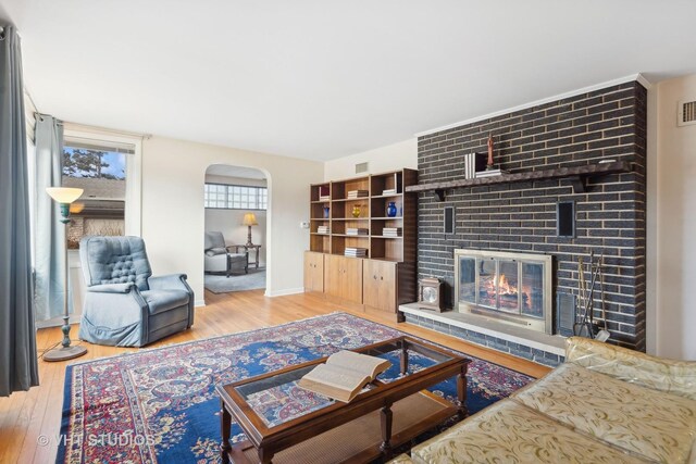 living room featuring a brick fireplace and light hardwood / wood-style flooring