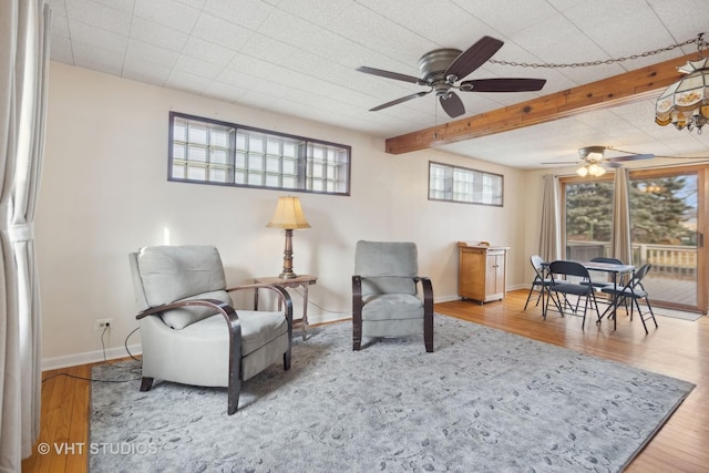 sitting room with ceiling fan, beam ceiling, wood-type flooring, and a healthy amount of sunlight