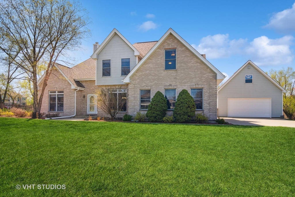 traditional home featuring a garage, brick siding, driveway, a front lawn, and a chimney