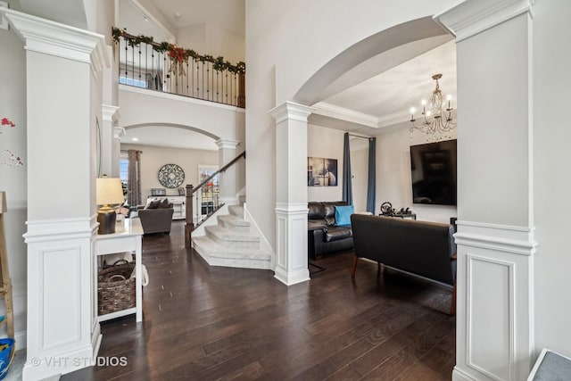 entryway featuring ornate columns, an inviting chandelier, and dark hardwood / wood-style flooring