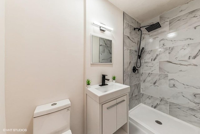 bathroom with vanity, toilet, and tiled shower