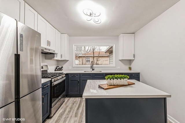 kitchen featuring sink, light wood-type flooring, appliances with stainless steel finishes, a kitchen island, and white cabinets