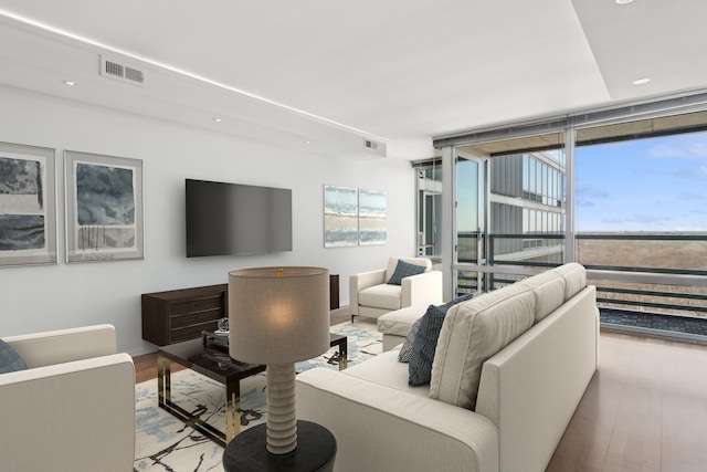 living area with visible vents, a wall of windows, wood finished floors, and recessed lighting