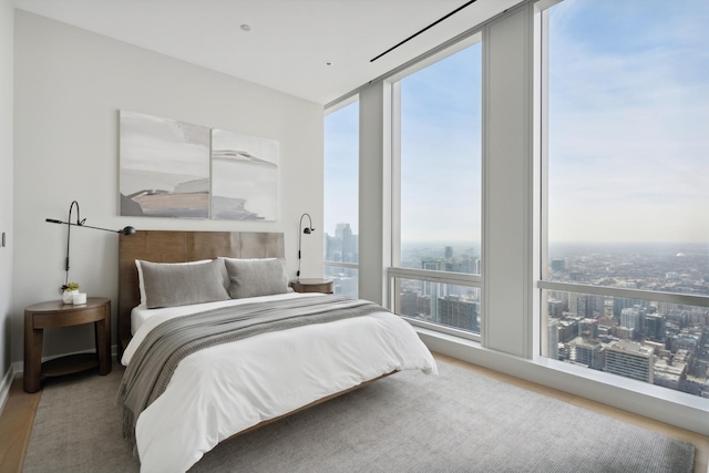 bedroom featuring multiple windows, hardwood / wood-style flooring, and a wall of windows