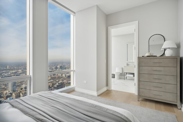 bedroom with expansive windows and light hardwood / wood-style floors