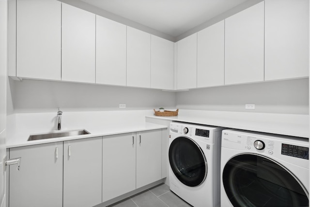 clothes washing area featuring sink, cabinets, washing machine and clothes dryer, and light tile patterned flooring