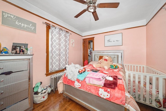 bedroom with ceiling fan, wood-type flooring, radiator, and ornamental molding