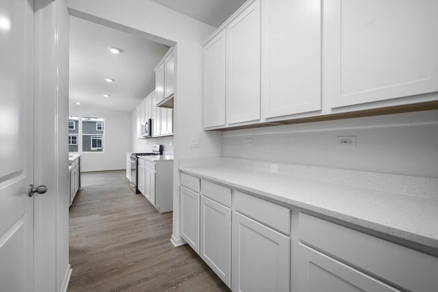 kitchen featuring light stone counters, hardwood / wood-style floors, stainless steel appliances, and white cabinets