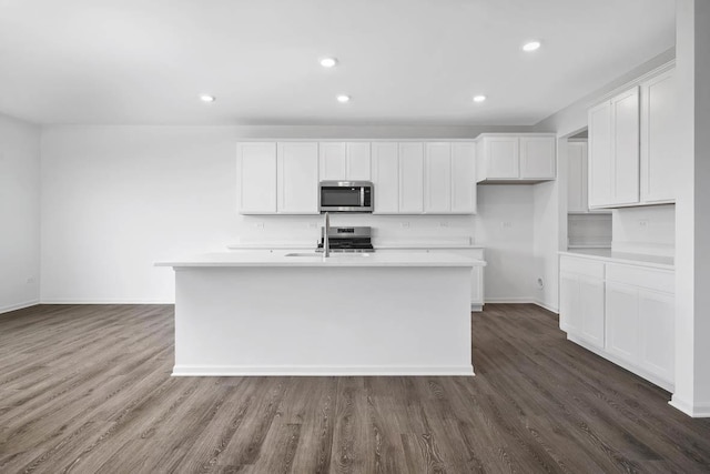 kitchen with white cabinetry, a center island with sink, dark hardwood / wood-style floors, and appliances with stainless steel finishes