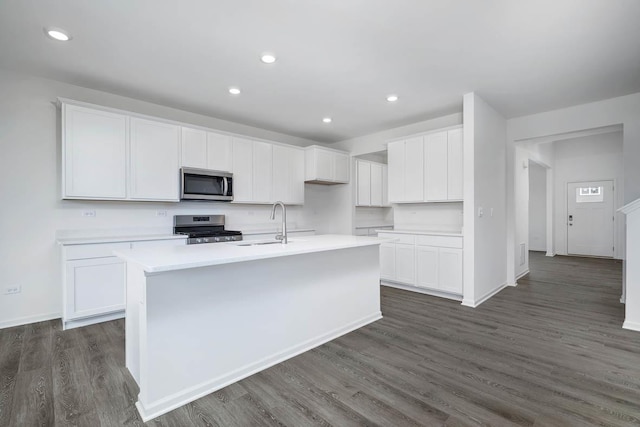 kitchen with an island with sink, white cabinetry, sink, dark hardwood / wood-style flooring, and stainless steel appliances