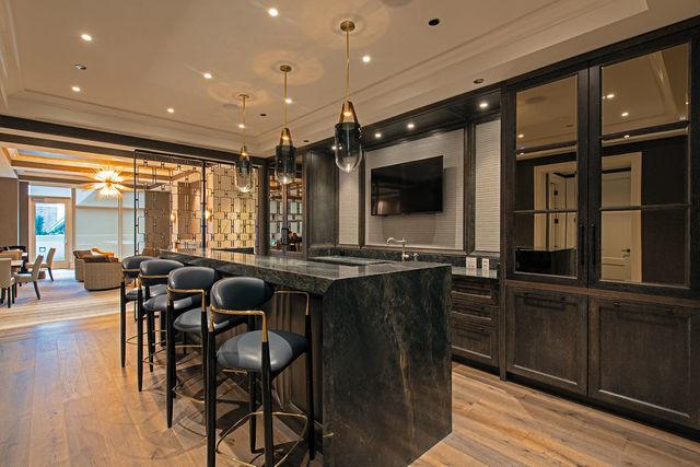 bar featuring pendant lighting, ornamental molding, light hardwood / wood-style flooring, and dark stone countertops