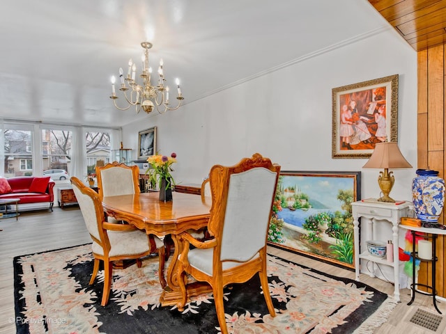 dining area with hardwood / wood-style flooring, crown molding, and a chandelier