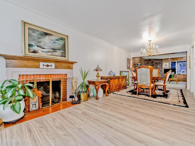 dining space featuring crown molding, a fireplace, an inviting chandelier, and light hardwood / wood-style flooring