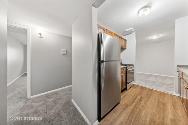 kitchen featuring light colored carpet, appliances with stainless steel finishes, and light brown cabinetry