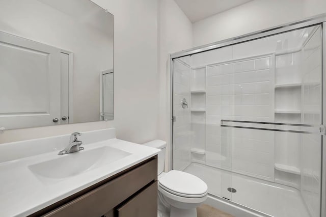 bathroom featuring vanity, a shower with shower door, and toilet