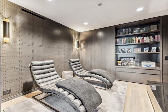 living area featuring built in shelves and light hardwood / wood-style flooring