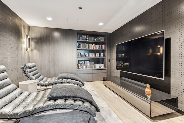 home theater room with built in shelves and wood-type flooring