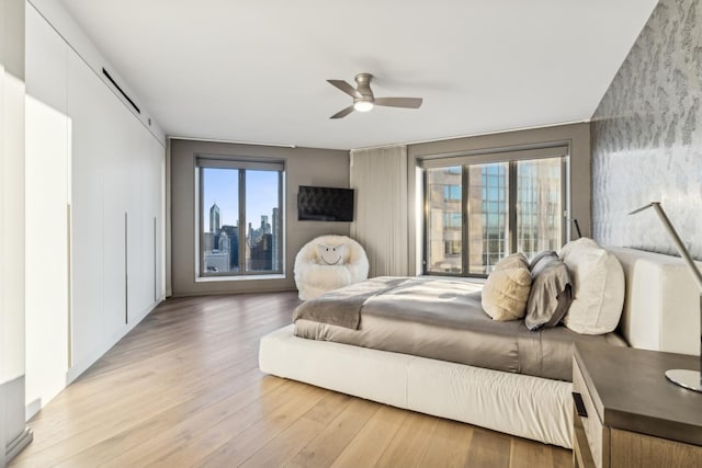 bedroom featuring a barn door, ceiling fan, and light hardwood / wood-style floors