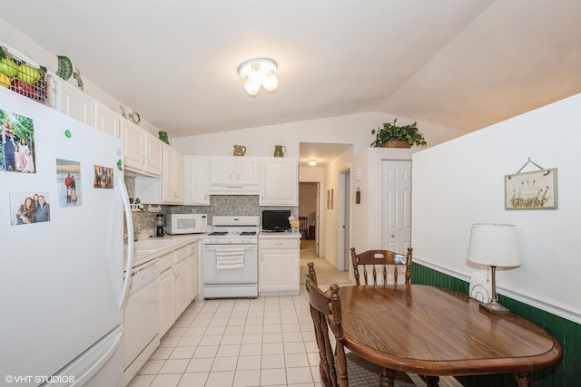 kitchen with light tile patterned floors, white appliances, white cabinetry, backsplash, and vaulted ceiling