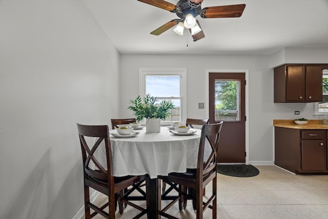 dining space featuring a ceiling fan, baseboards, and light tile patterned floors