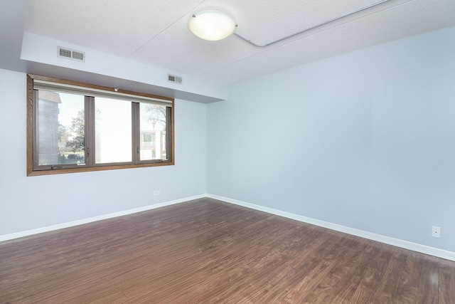 spare room featuring dark wood-type flooring and a textured ceiling