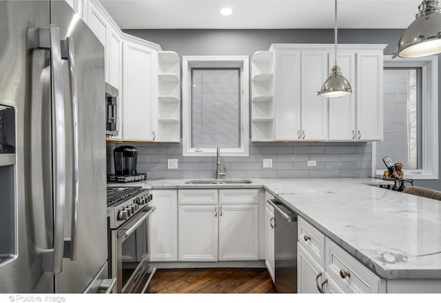 kitchen featuring decorative light fixtures, white cabinetry, sink, stainless steel appliances, and light stone countertops