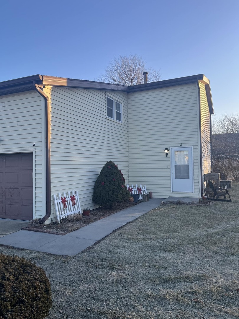 rear view of house with a garage and a lawn